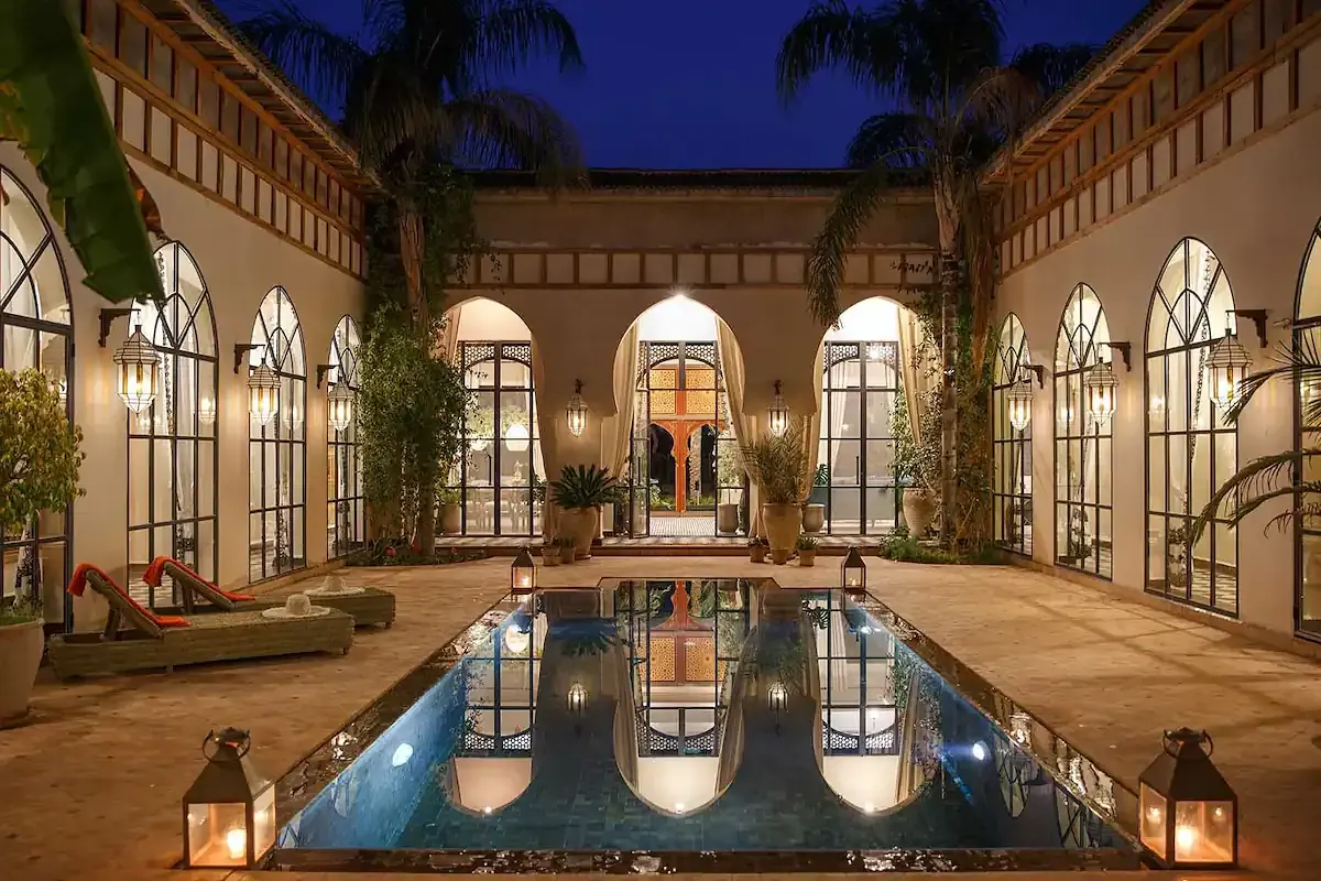 The courtyard pool at Daba Village, a riad outside Marrakech, lit by lanterns at night